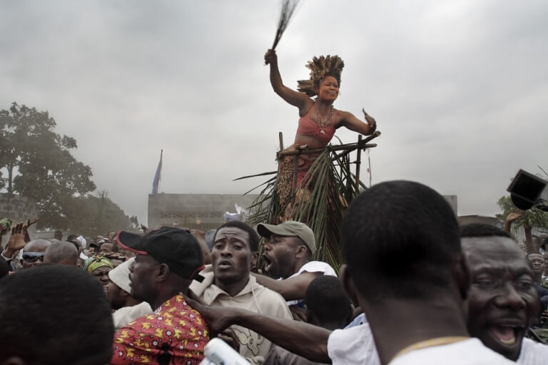 Traditional dancer and crowd, saluting Jean-Pierre Bemba as he walks to a rally, Kinshasha
