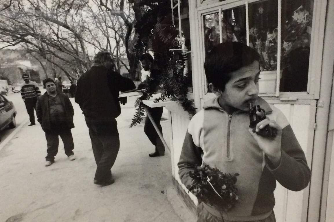 Boy with broken gun selling flowers at the market in Grozney